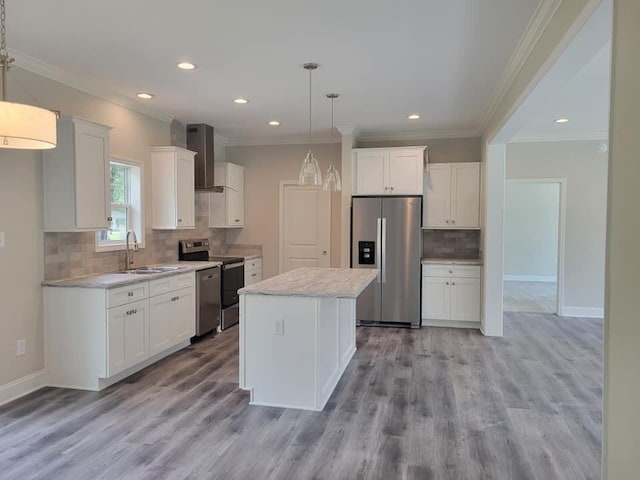 kitchen featuring stainless steel appliances, a center island, white cabinets, wall chimney range hood, and pendant lighting