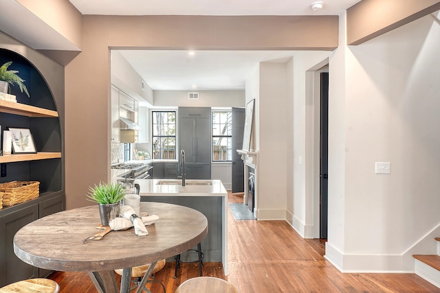 dining space featuring built in shelves, baseboards, visible vents, light wood finished floors, and a fireplace