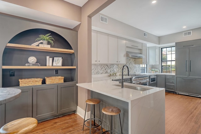 kitchen featuring paneled fridge, visible vents, light stone counters, and wall chimney exhaust hood