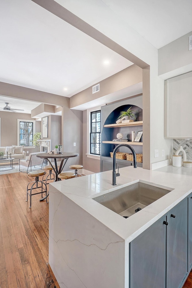 kitchen with light stone counters, open floor plan, plenty of natural light, and a sink