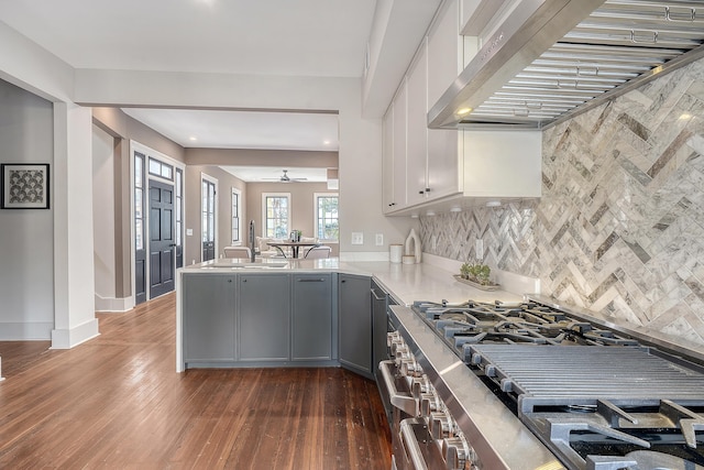 kitchen featuring a ceiling fan, stainless steel range with gas cooktop, a peninsula, a sink, and under cabinet range hood