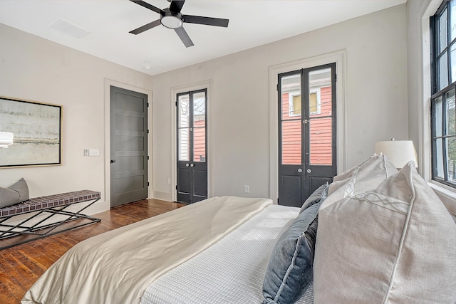 bedroom with a ceiling fan, wood finished floors, and visible vents