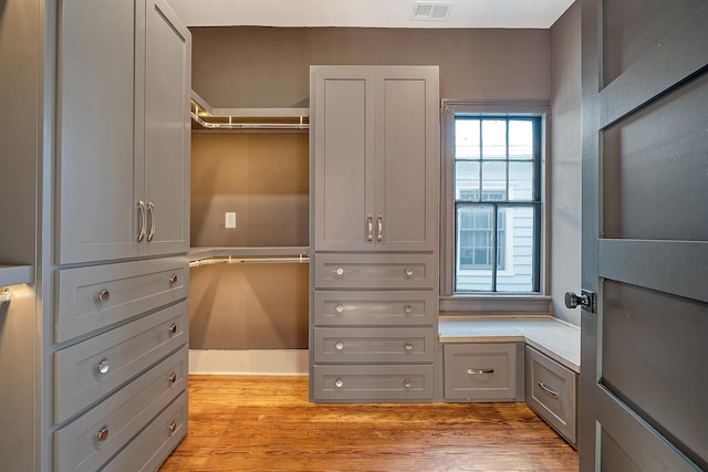 walk in closet with light wood finished floors and visible vents