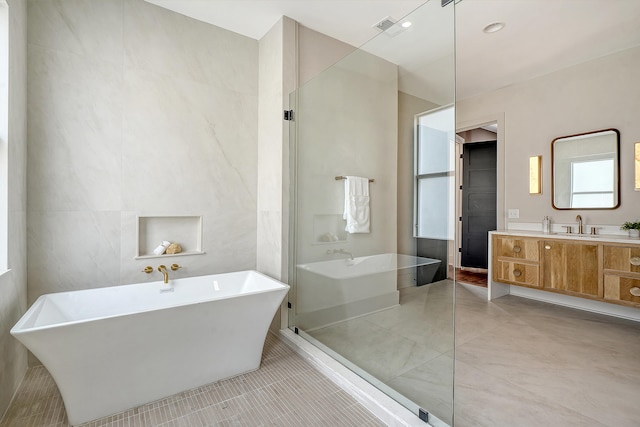 bathroom with vanity, visible vents, a soaking tub, tile patterned flooring, and tile walls