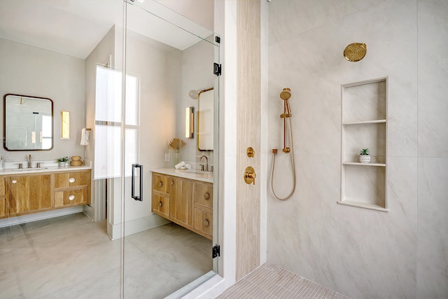 bathroom with tile patterned floors, two vanities, a tile shower, and a sink