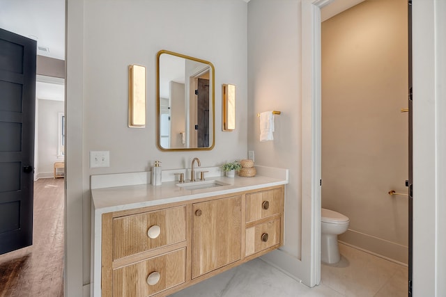 bathroom with toilet, vanity, and baseboards