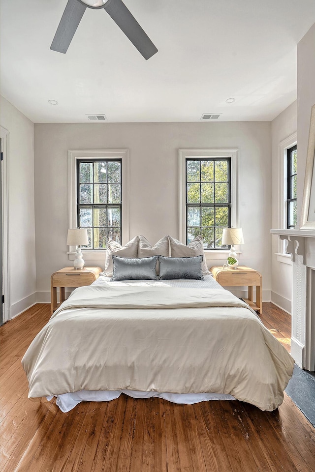 bedroom featuring visible vents, multiple windows, and wood finished floors