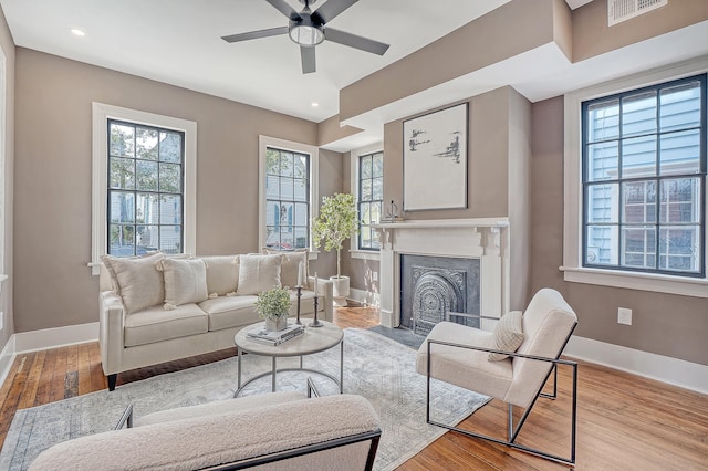 living area with plenty of natural light, wood finished floors, visible vents, and baseboards