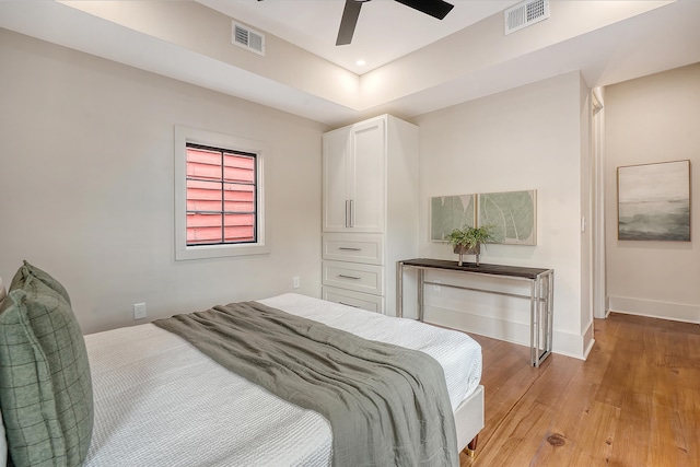 bedroom with light wood finished floors, visible vents, ceiling fan, and baseboards