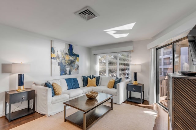 living area with visible vents, a skylight, and wood finished floors