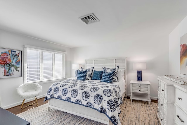 bedroom with light wood-style floors, visible vents, and baseboards