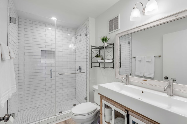 bathroom with visible vents, a shower stall, toilet, and vanity