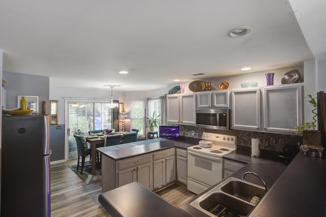 8059 Shadow Oak Dr, North Charleston, SC 29406 - kitchen with appliances with stainless steel finishes, dark countertops, a peninsula, decorative backsplash, and dark wood-style flooring