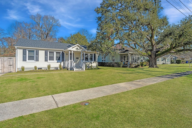 view of front of house with a shingled roof, fence, and a front lawn