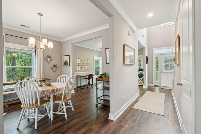 dining space featuring a healthy amount of sunlight, crown molding, dark hardwood / wood-style flooring, and a notable chandelier