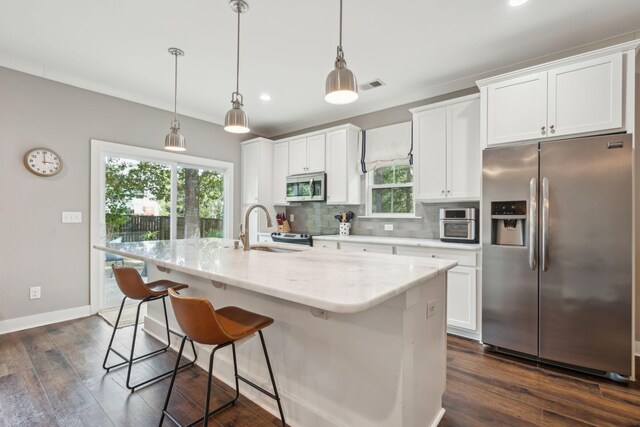 kitchen featuring pendant lighting, stainless steel appliances, dark hardwood / wood-style floors, and a kitchen island with sink