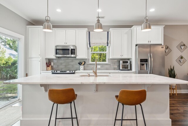 kitchen featuring a center island with sink, appliances with stainless steel finishes, and hanging light fixtures