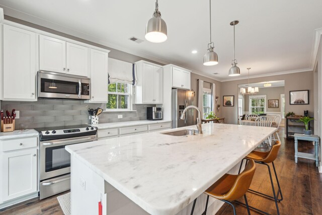 kitchen featuring decorative light fixtures, an island with sink, and appliances with stainless steel finishes