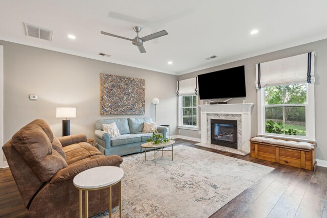 living room featuring a high end fireplace, ceiling fan, dark wood-type flooring, and a wealth of natural light