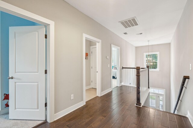 hallway featuring an inviting chandelier and dark wood-type flooring