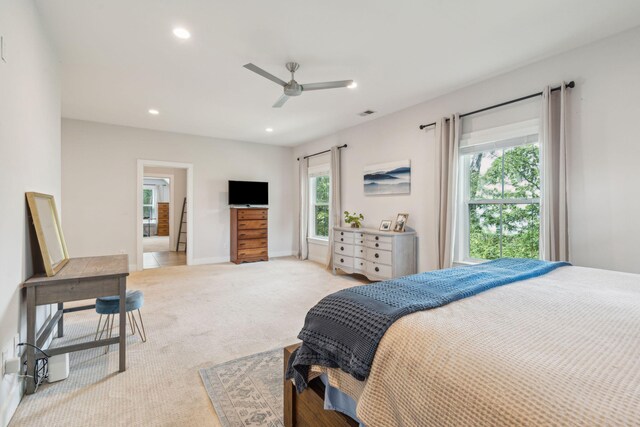 bedroom with multiple windows, light colored carpet, and ceiling fan