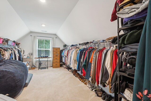 walk in closet with lofted ceiling and light colored carpet