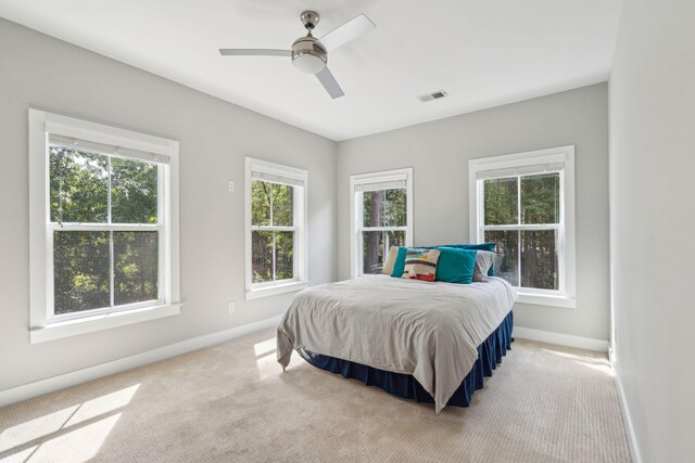 bedroom featuring light carpet, multiple windows, and ceiling fan