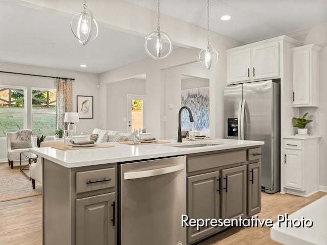 kitchen with white cabinets, appliances with stainless steel finishes, open floor plan, light countertops, and gray cabinetry