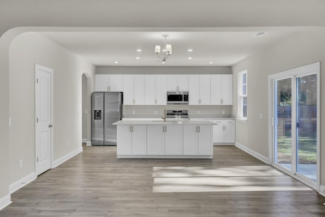 5629 Ellington School Rd, Ravenel, SC 29470 - kitchen featuring stainless steel appliances, arched walkways, white cabinetry, light wood-style flooring, and recessed lighting