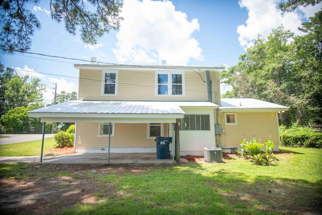 rear view of house featuring central AC unit and a lawn