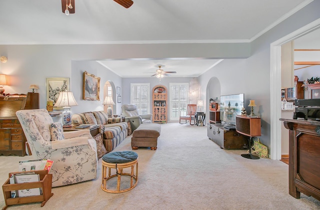carpeted living room featuring a ceiling fan, ornamental molding, and arched walkways