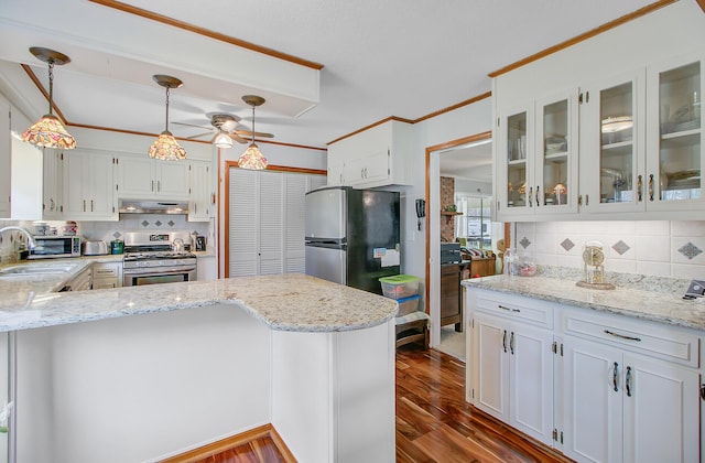 kitchen with under cabinet range hood, a sink, white cabinets, a peninsula, and appliances with stainless steel finishes