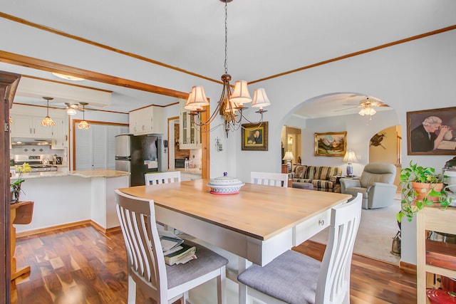 dining space featuring arched walkways, dark wood-style floors, crown molding, and ceiling fan with notable chandelier