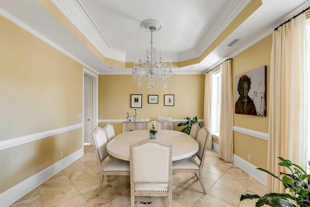 dining room featuring baseboards, visible vents, a raised ceiling, and ornamental molding