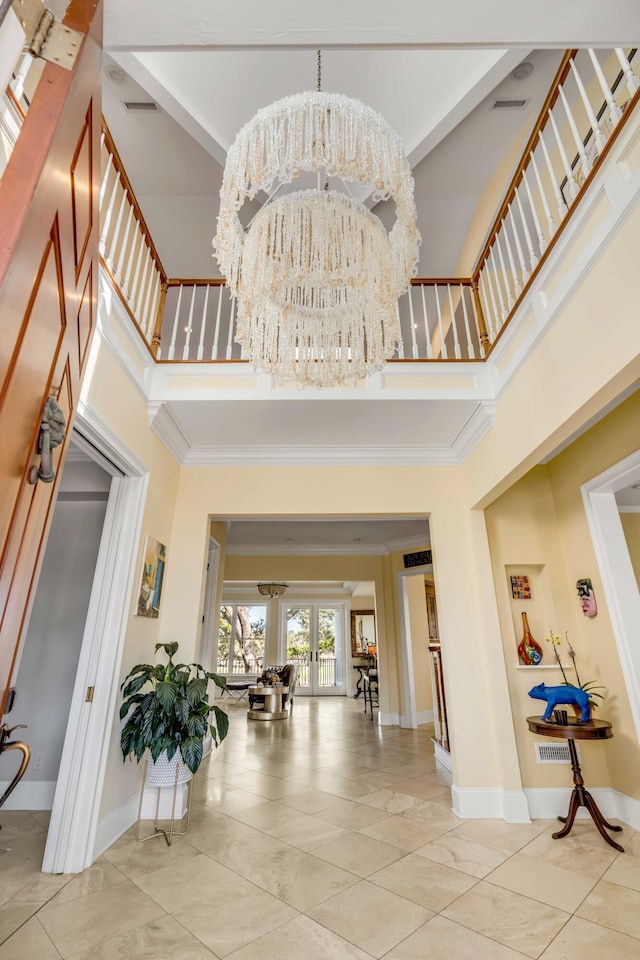 entryway featuring baseboards, a high ceiling, crown molding, french doors, and a notable chandelier