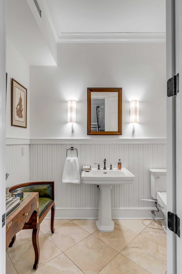 bathroom with crown molding, visible vents, toilet, wainscoting, and tile patterned floors