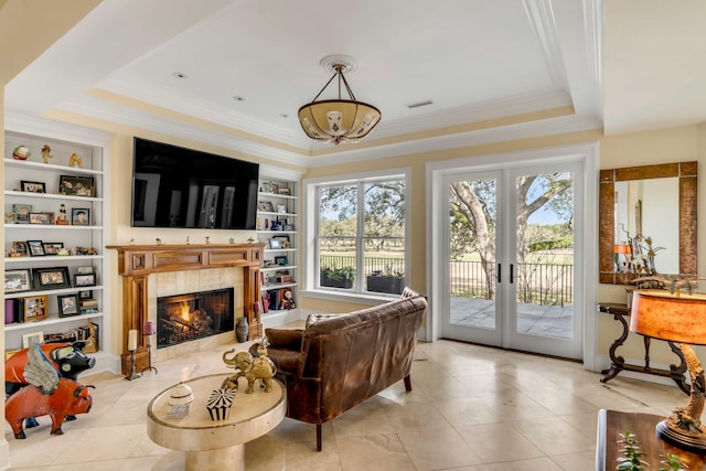 sitting room featuring built in features, a tray ceiling, and a wealth of natural light