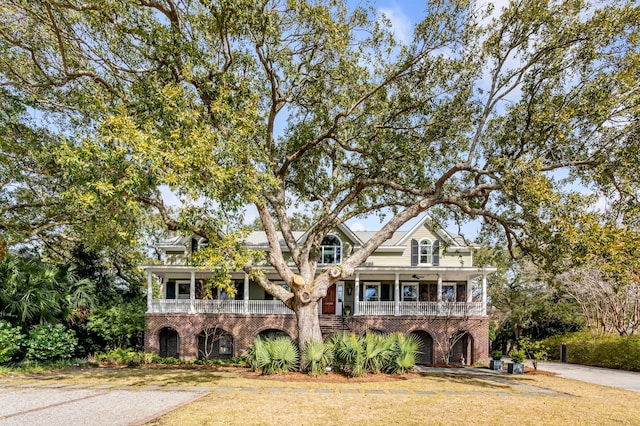 view of front facade featuring driveway, brick siding, a porch, and a front yard