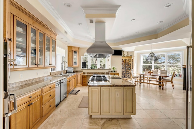 kitchen featuring a center island with sink, a raised ceiling, glass insert cabinets, a sink, and light stone countertops