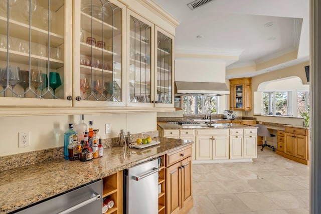 kitchen featuring glass insert cabinets, a tray ceiling, and light stone countertops