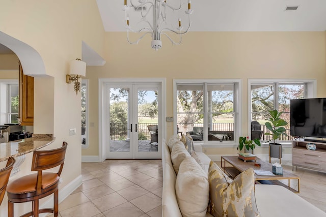 living area featuring arched walkways, light tile patterned floors, a chandelier, visible vents, and french doors