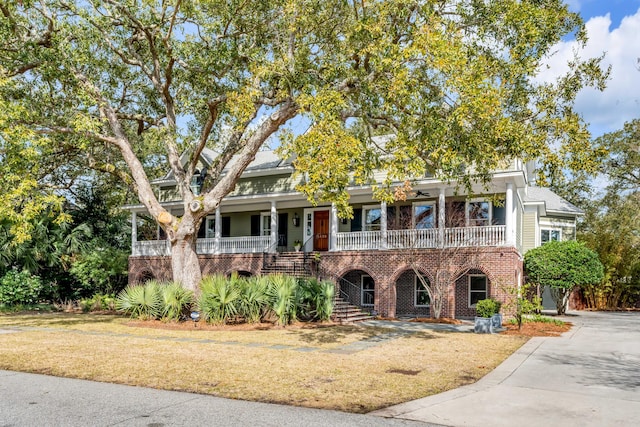 view of front facade featuring covered porch, a front yard, and brick siding