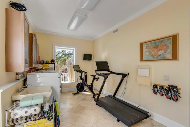 workout area with light tile patterned flooring, a sink, visible vents, baseboards, and crown molding