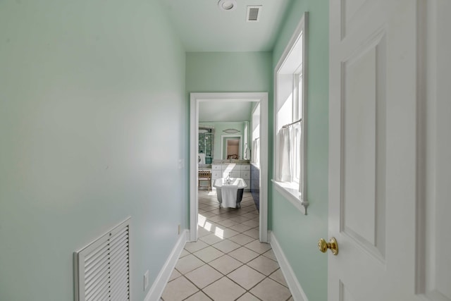 hall with light tile patterned floors, baseboards, and visible vents