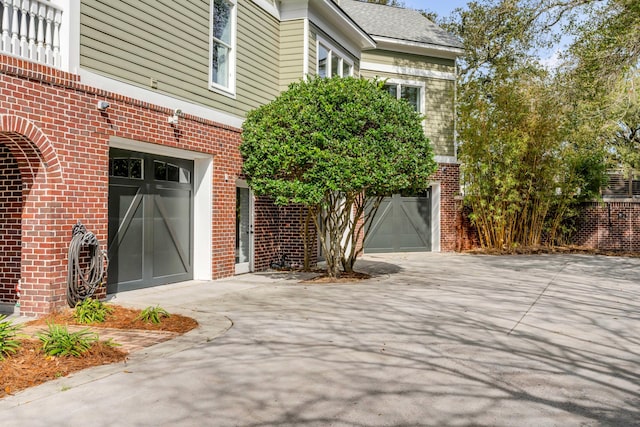 doorway to property featuring concrete driveway, brick siding, and an attached garage