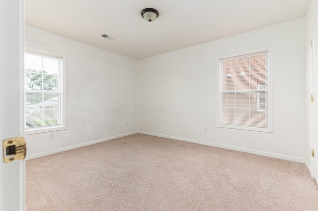unfurnished room featuring light colored carpet and plenty of natural light