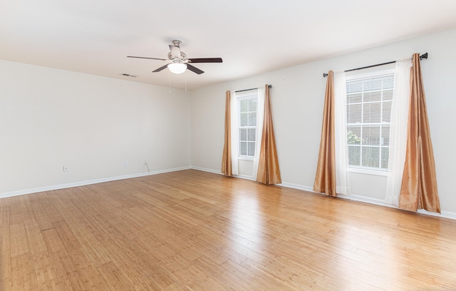 empty room with plenty of natural light, ceiling fan, and light wood-type flooring