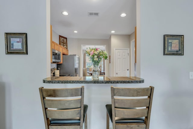 kitchen featuring visible vents, a breakfast bar area, recessed lighting, appliances with stainless steel finishes, and a peninsula