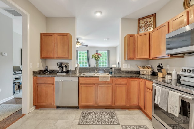 kitchen featuring visible vents, dark stone counters, appliances with stainless steel finishes, a ceiling fan, and a sink