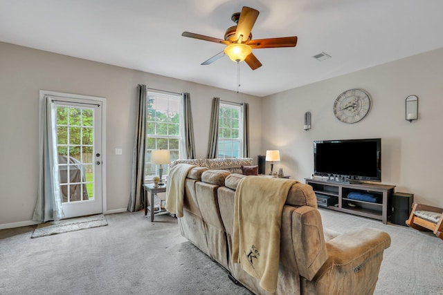 living area with visible vents, baseboards, light colored carpet, and a ceiling fan